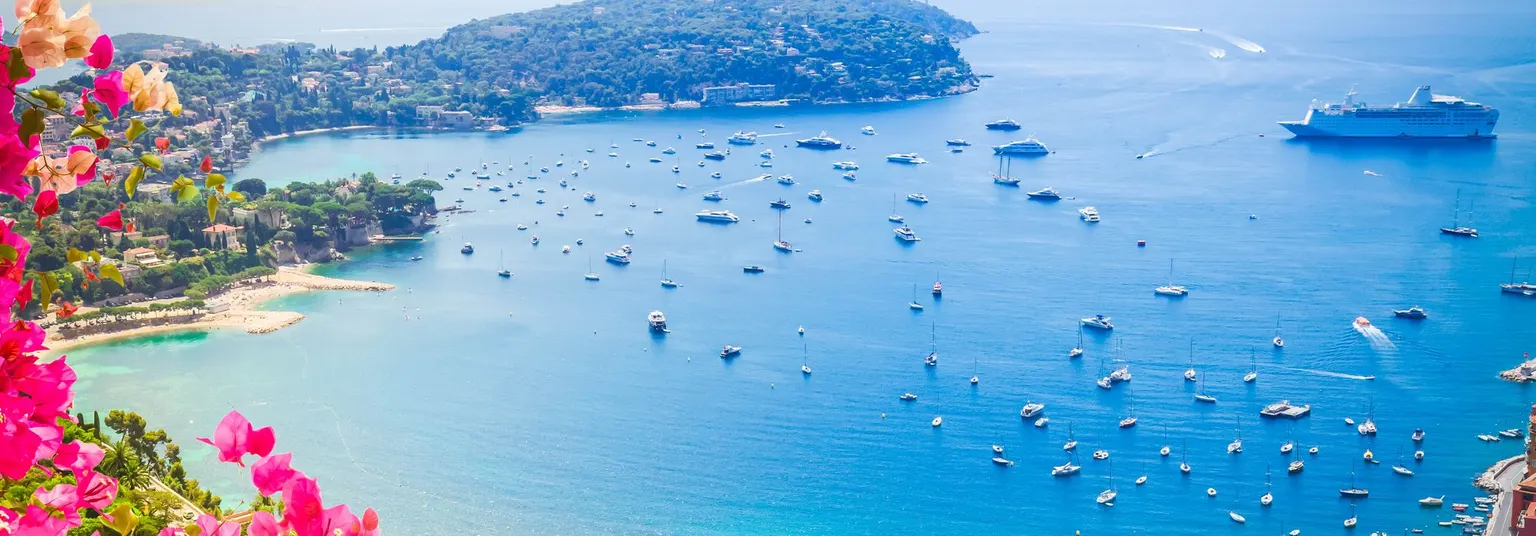 Een diepblauwe zee, boten, kleurrijke bloemen en palmbomen: de Côte d'Azur in Frankrijk